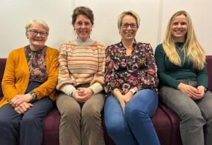 Fire smilende kvinnelige ansatte sitter sammen i en sofa - Klikk for stort bilde